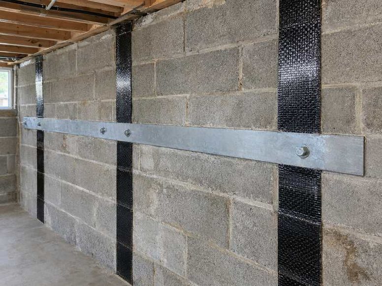 Bowing basement wall reinforced with carbon-fiber straps